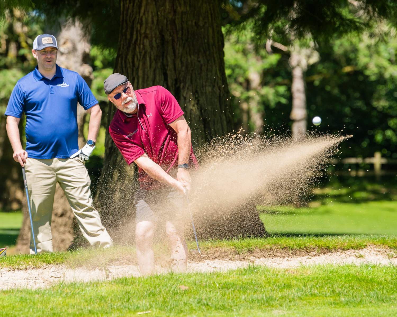 Chris Arhutick hits his ball out of the sand during a charity golf tournament at Riverside Golf Course in Chehalis on Friday.